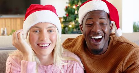Diverse couple in santa hats celebrating christmas at home