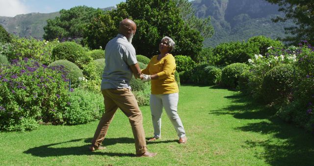 Senior couple enjoying each other's company in nature while dancing in a lush garden. Suitable for use in projects depicting active retirement, love in later life, outdoor activities, happiness, and healthy living.
