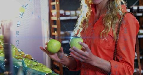 Woman choosing green apples at farmers market comparing fruit for purchase