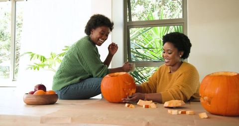 African american women joyfully carving pumpkins together