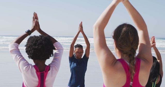 Group of women practicing yoga poses on beach with ocean in background. Perfect for promoting wellness, mindfulness, fitness events, and outdoor activities. Useful for blogs, social media posts, and advertisements focused on health and well-being.