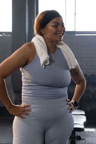 Smiling african american woman standing hands on hips after intense gym workout