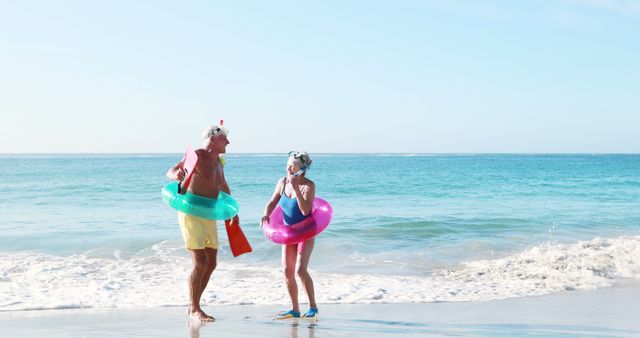 Senior Couple Enjoying Beach Vacation with Swimming Gear and Inflatable Rings - Download Free Stock Images Pikwizard.com