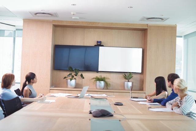 Business team in a modern boardroom looking at a whiteboard during a meeting. Ideal for illustrating corporate meetings, teamwork, presentations, and professional discussions. Useful for business-related articles, corporate websites, and promotional materials.