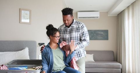 Happy Couple Unpacking Suitcase for Vacation in Hotel Room
