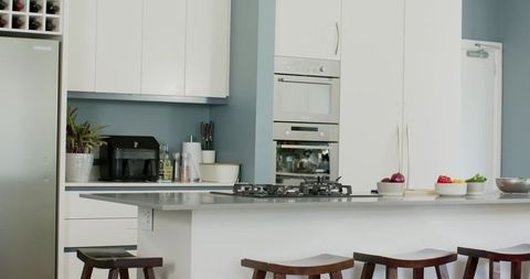 Kitchen island anchoring blue kitchen with gray countertop, gas cooktop, wood stools
