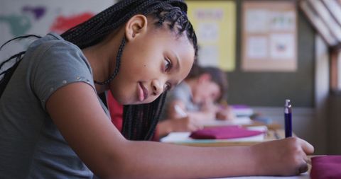 Young Girl Focused on Writing in Classroom