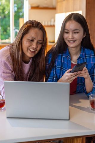 Mother and Daughter Enjoying Tech at Home in Cozy Kitchen