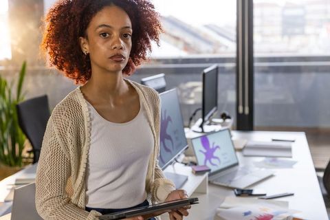 Confident Businesswoman Holding Tablet in Modern Workspace