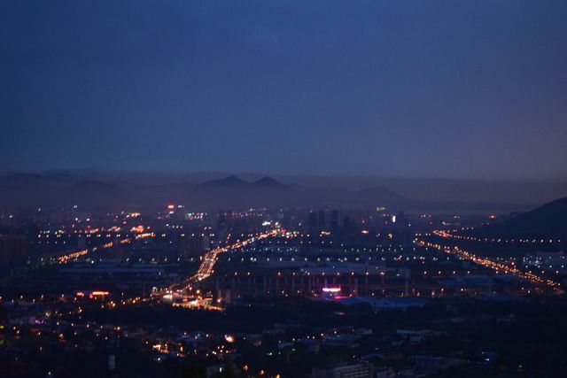 Twilight Cityscape with Illuminated Roads and Distant Mountains - Download Free Stock Photos Pikwizard.com