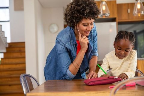 Mother Guiding Young Daughter with Homework at Cozy Kitchen Table