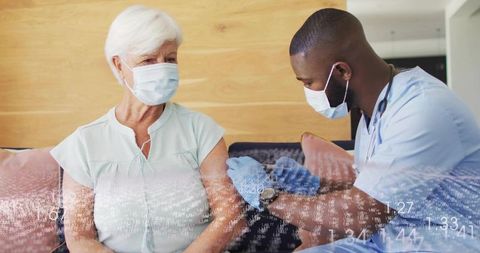 Administering Home Vaccination to Senior Woman on Sofa by Masked Nurse in Scrubs
