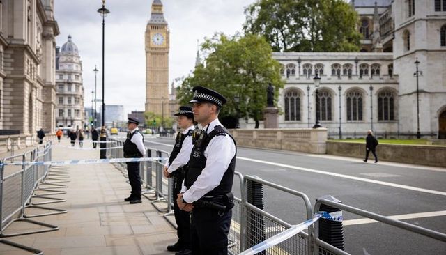 Police officers securing westminster near big ben with barriers and police tape