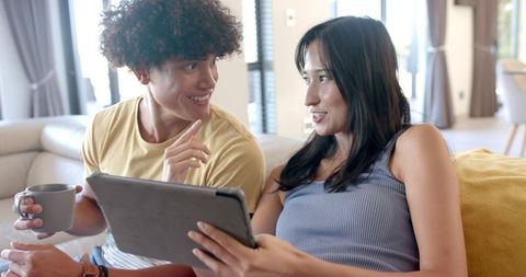 Friends Relaxing at Home Using Tablet and Drinking Coffee