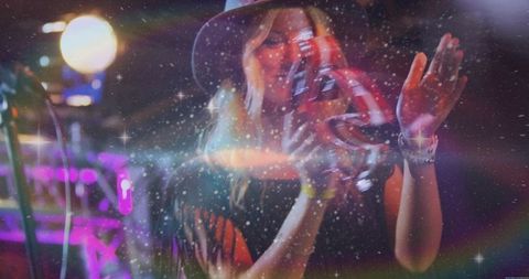 Blonde musician playing tambourine on stage with energetic lighting