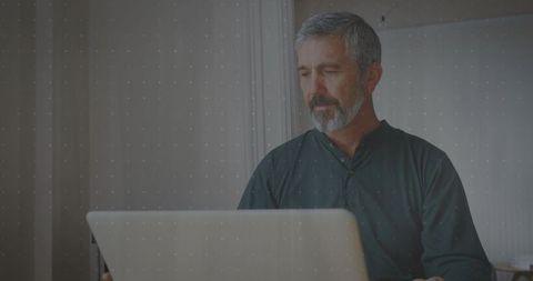 Mature Man Concentrating on Work at Home Office Desk with Laptop