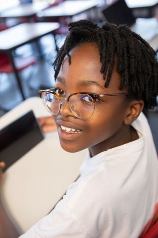 Smiling african american boy using tablet in modern classroom