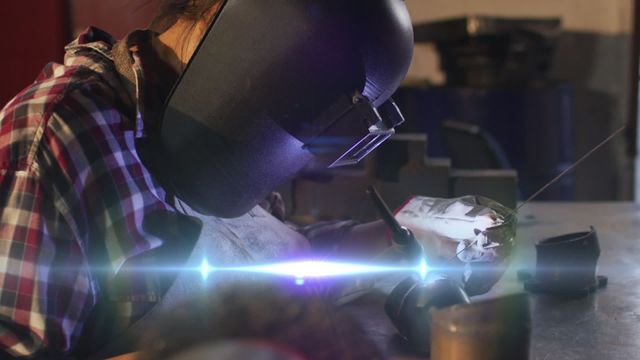 This video depicts a welder in an industrial workshop wearing protective gear while working with metal. Sparks fly as the welding activity takes place, showcasing the intensity and focus required for the job. It's suitable for use in articles and advertisements about industrial work, skilled labor, safety protocols, and metalworking. Can also be used to illustrate occupational health and safety topics.