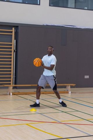 African american athlete practicing basketball dribbling drill on indoor gym court