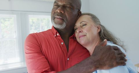 Happy Senior Diverse Couple Embracing in Bright Living Room