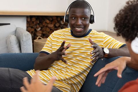 Friends Chatting with Headphones on Comfortable Sofa at Home