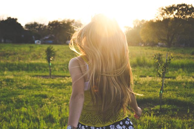 Woman with long blonde hair enjoying a walk in the countryside during sunset, hair flowing freely. Perfect for themes related to nature, relaxation, freedom, and outdoor lifestyle. Ideal for use in wellness, travel, relaxation, and inspirational concepts.