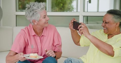 Senior Lesbian Couple Enjoying Birthday Celebration with Cake and Selfie