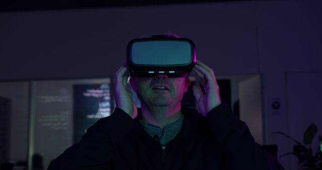 A person wearing a VR headset immersed in a virtual reality experience in a dimly lit room. The purple and blue neon lights suggest a futuristic and immersive environment. Ideal for use in technology blogs, articles about virtual reality and gaming, promotional materials for VR products, or innovation presentations.