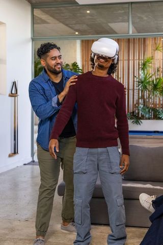 Friends steadying man wearing vr headset in modern loft lounge, casual vr companionship