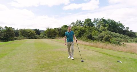 Golfer Walking on Tee Box Relaxed with Driver on Green Golf Course
