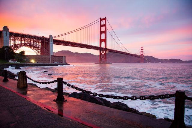 Golden Gate Bridge standing majestically during sunrise with vibrant colors in the sky and calm waters below. Ideal for travel blogs, photography websites, postcards, and promotional materials showcasing San Francisco's beauty and iconic landmarks.