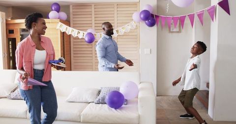 African american family preparing home birthday party with purple balloons and banner