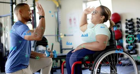 High-fiving trainer and woman in wheelchair celebrating adaptive strength training at gym