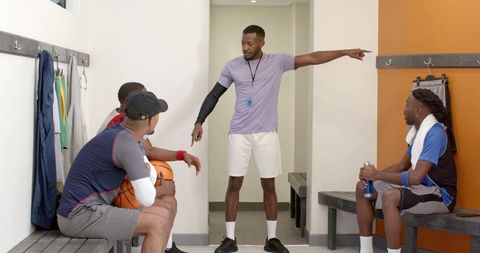 Coach pointing and instructing basketball team in locker room during intense pregame talk