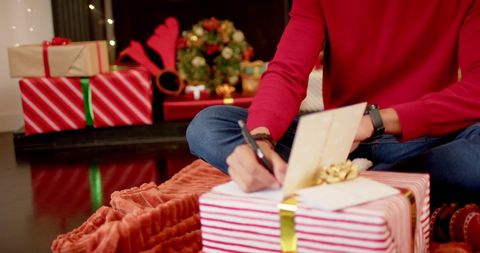 Person Writing Holiday Card Amid Festive Christmas Surroundings