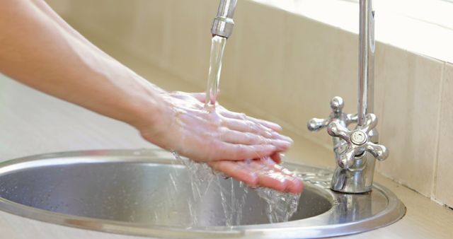 Woman washing her hands at the sink at home in the kitchen