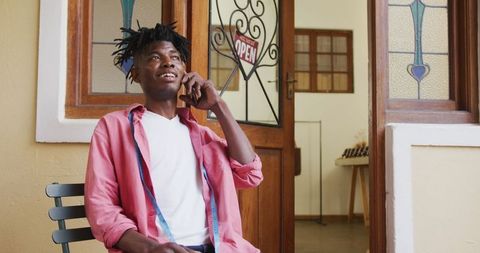 African American Craftsman Relaxing with Phone Call at Workshop