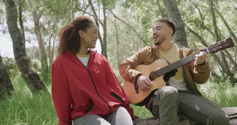 Joyful Couple Hiking and Playing Guitar in Sunlit Forest