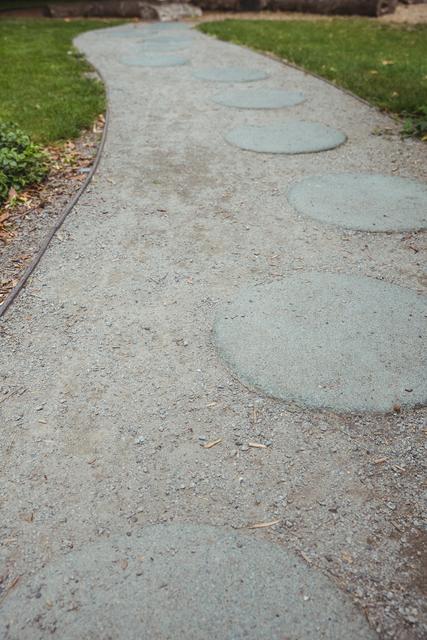 Stepping stone garden path winding through a tranquil outdoor setting, ideal for use in landscaping, gardening, and outdoor living projects. Perfect for illustrating concepts of serenity, nature, and garden design in blogs, websites, and promotional materials.
