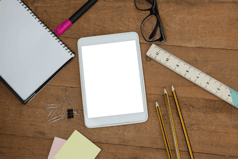 Overhead of school supplies and tablet on transparent wooden desk