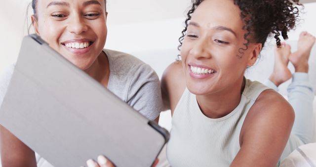 Cheerful Friends Lying on Bed Watching something on Tablet - Download Free Stock Images Pikwizard.com