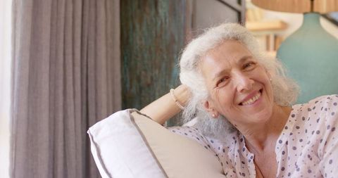 Relaxed Senior Woman with Pillow Smiling at Home