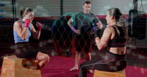 Female boxers training on plyo boxes with coach overseeing sparring and tech overlay