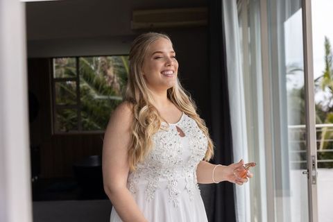 Bride in elegant gown applying perfume in wedding suite