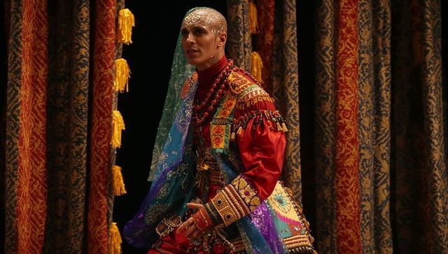 Ornate Theatrical Performer Wearing Embroidered Costume and Beaded Veil on Stage