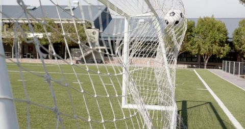 Soccer ball scoring goal in outdoor field with net