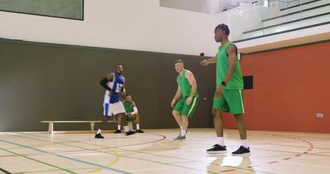 Players dribbling and chasing rebound on indoor court during competitive basketball play