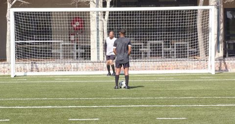 Soccer players practicing goal kicks outdoors