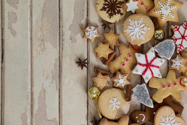 Assorted decorated Christmas cookies lying on rustic wooden surface, featuring gingerbread men, stars, snowflakes, and other festive shapes. Perfect for holiday-themed designs, cooking blogs, Christmas cards, or bakery promotions. Captures the essence of holiday baking and festive cheer.