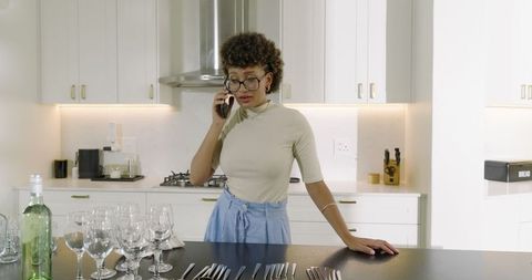 Woman Chatting on Smartphone Preparing Dinner Party in Modern Kitchen
